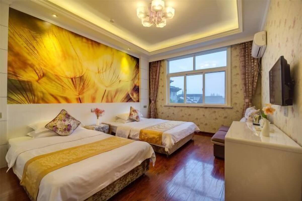 A hotel room with two beds, a large window, a TV, and a decorative wall mural.