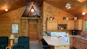 Un interior acogedor de cabaña con cocina, comedor y una puerta de madera grande.