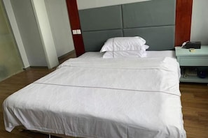Een net opgemaakt bed met witte lakens in een hotelkamer.