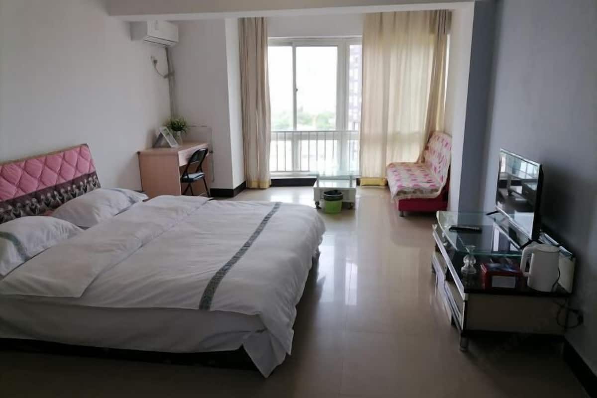 A hotel room with a bed, a desk, a chair, a TV, and a balcony.
