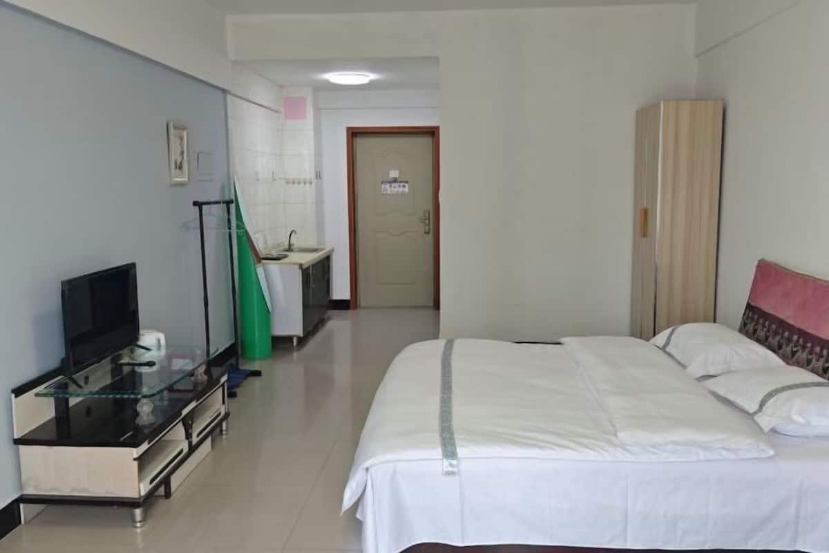A hotel room with a bed, a television, a desk with a computer, a bathroom, and a wardrobe.