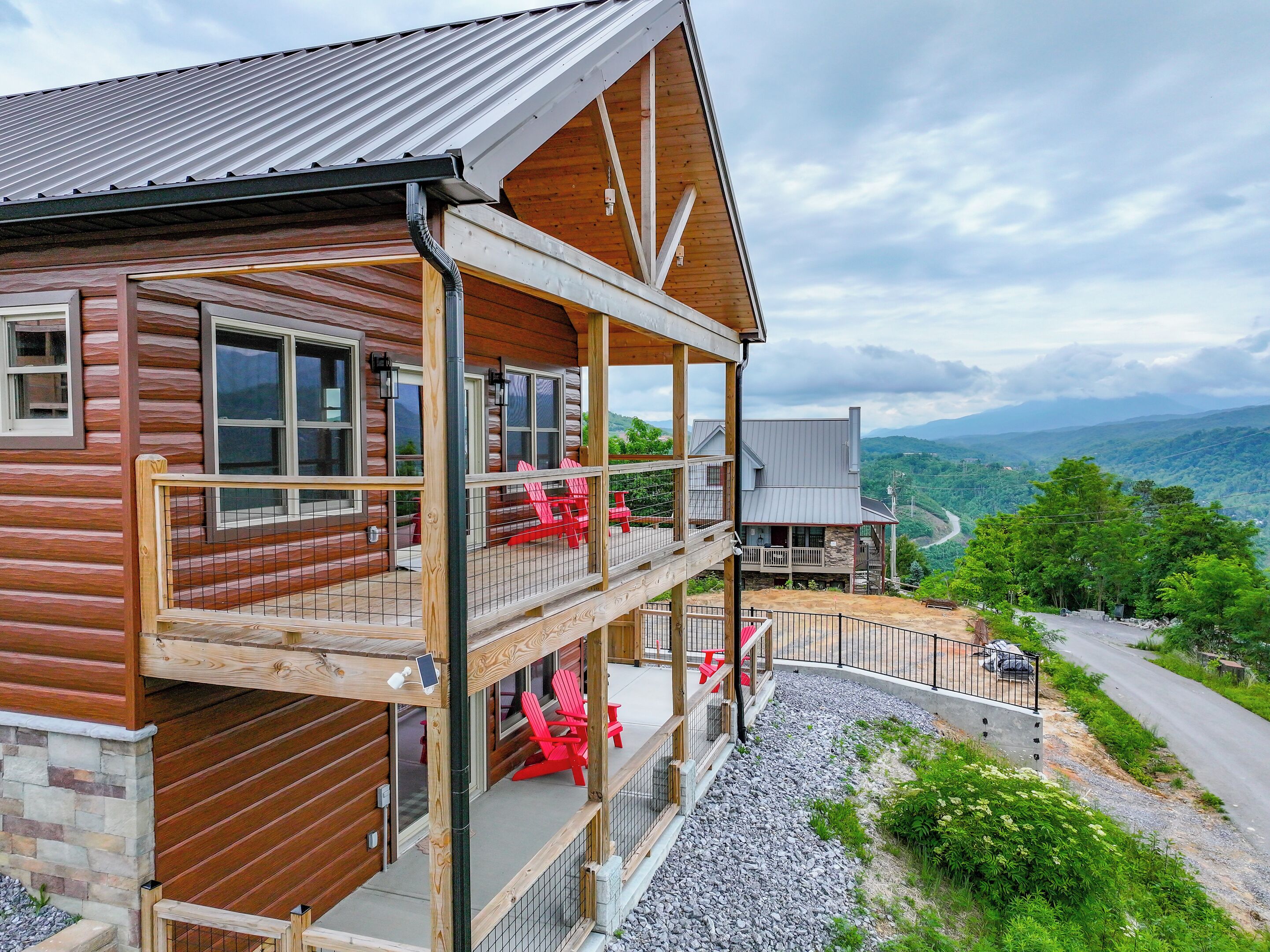 A two-story log cabin with a balcony and a stone foundation.