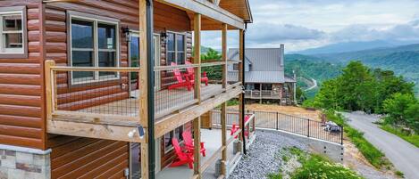 A two-story log cabin with a balcony and a stone foundation.