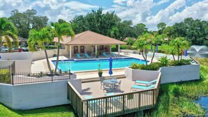 A pool area with lounge chairs, a small pavilion, and a fenced deck.