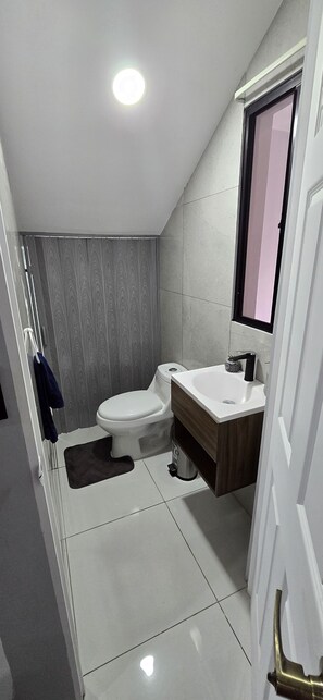 A modern bathroom with a toilet, sink, and mirror.