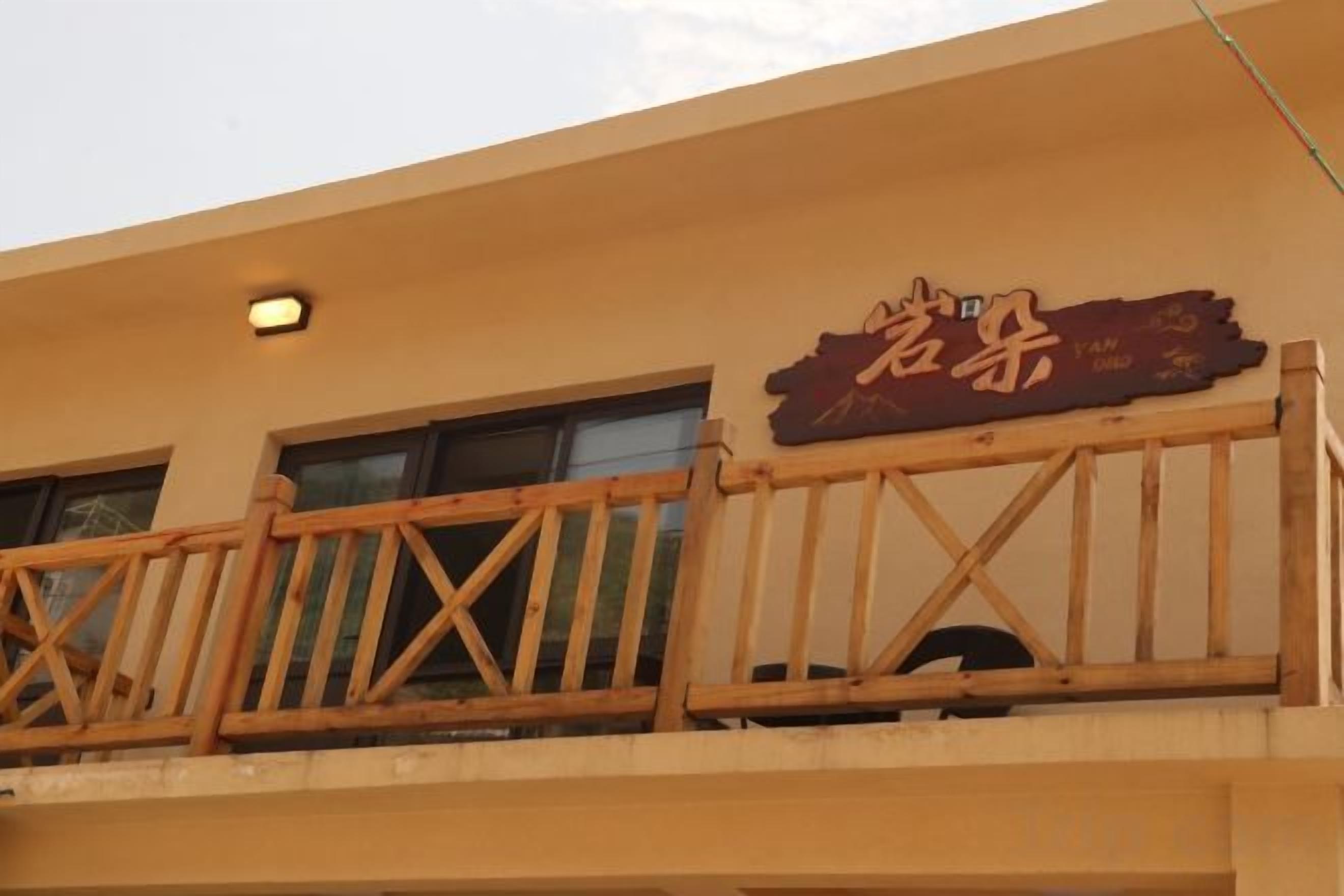 A building with a balcony featuring a wooden railing and a sign with Chinese characters.