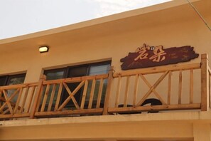 Ein Gebäude mit einem Balkon, der mit einem Holgitter und einem Schild mit chinesischen Schriftzeichen versehen ist.