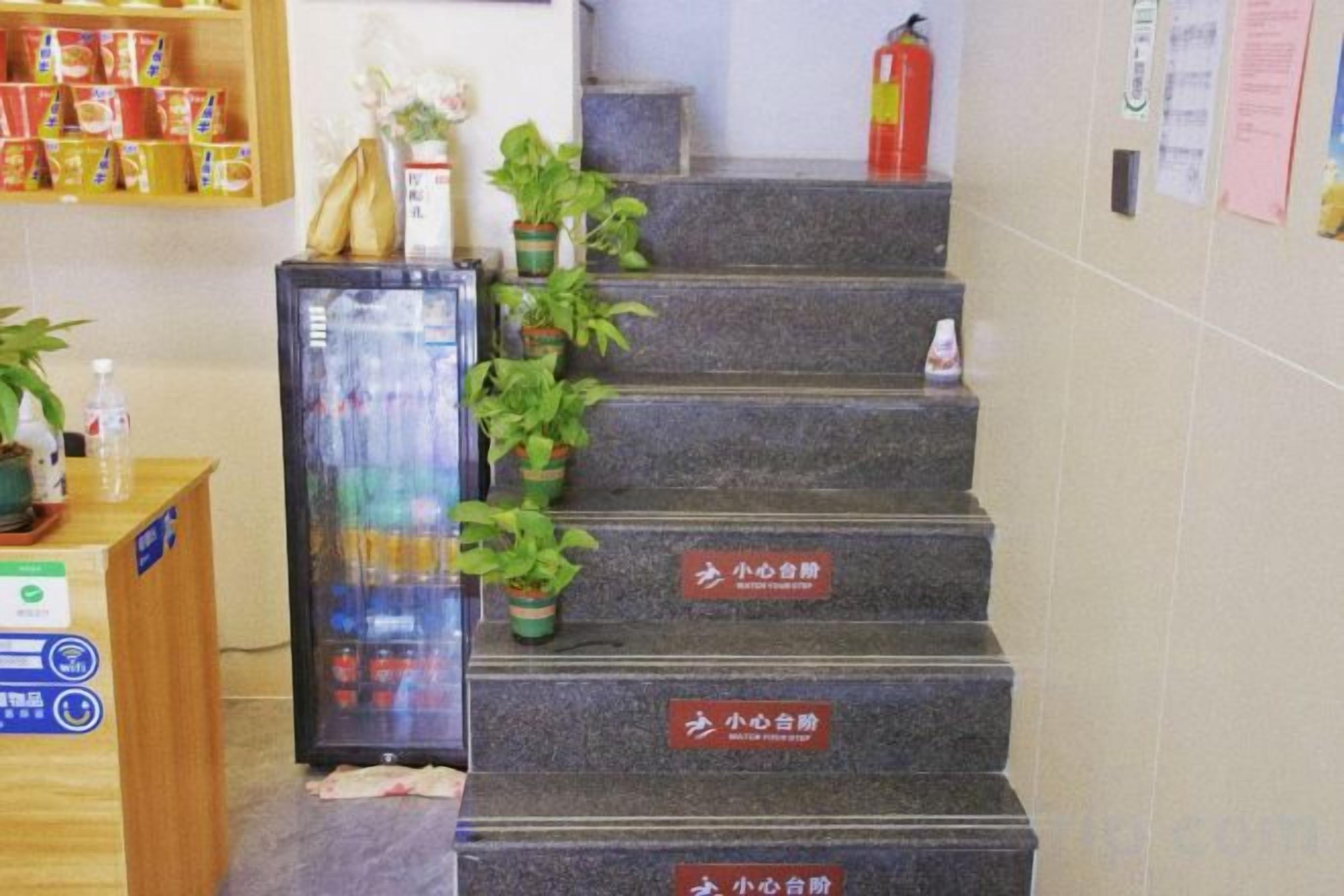 A staircase with potted plants and signs indicating different floors.