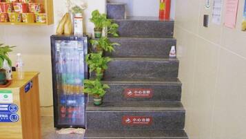 A staircase with potted plants and signs indicating different floors.