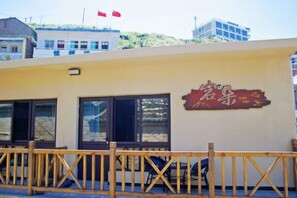 A building with a sign that includes Chinese characters, a wooden fence, and a flag. - Zhoushan Dongji Yanduo Homestay (Dongfushan Branch) (Zhoushan)