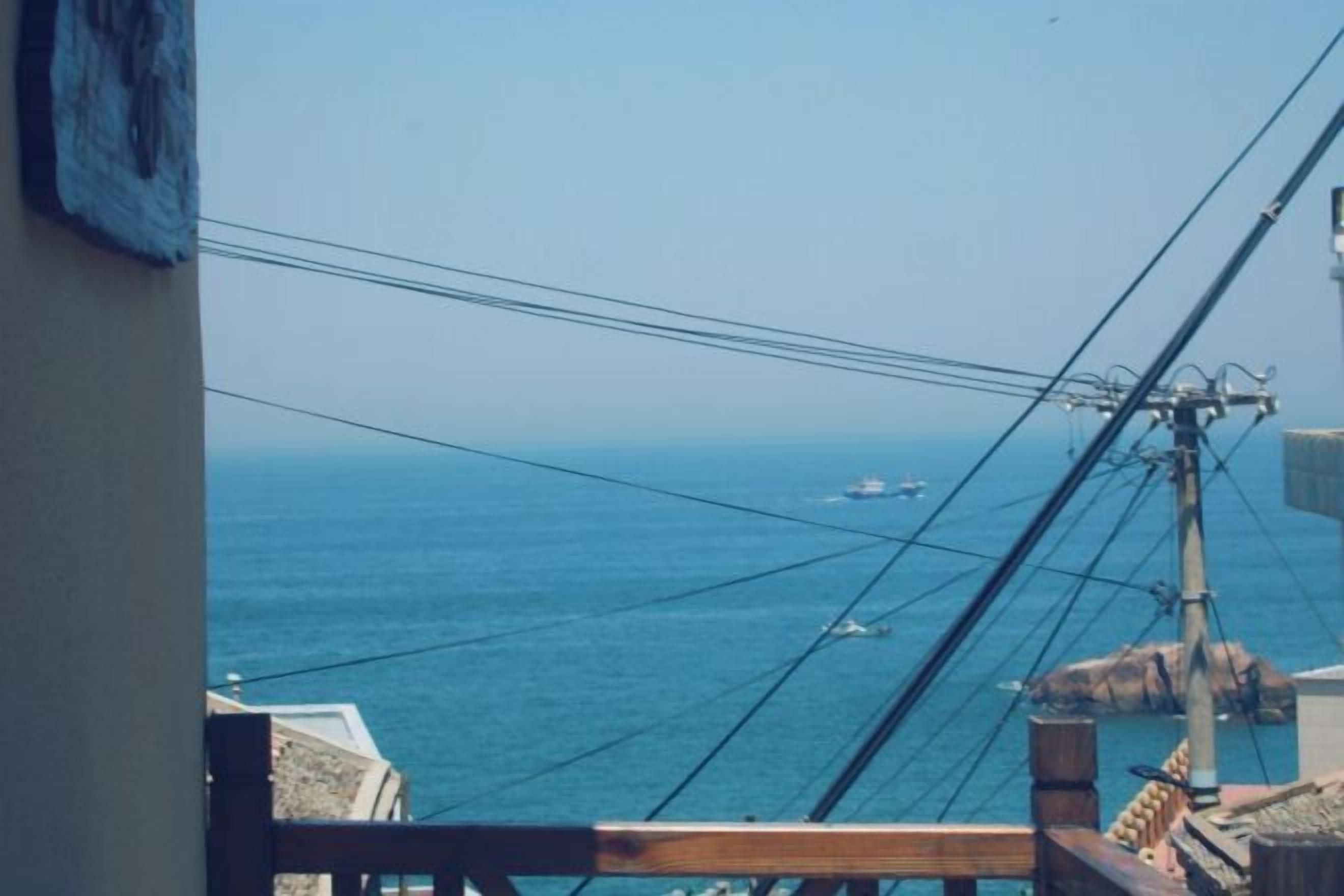 A coastal view with a wooden railing, a clear sky, and a distant boat.