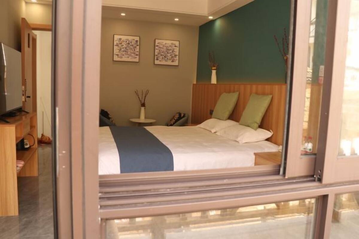 Habitación de hotel con cama, mesita de noche, una silla, televisor y una pared decorada con dos cuadros.