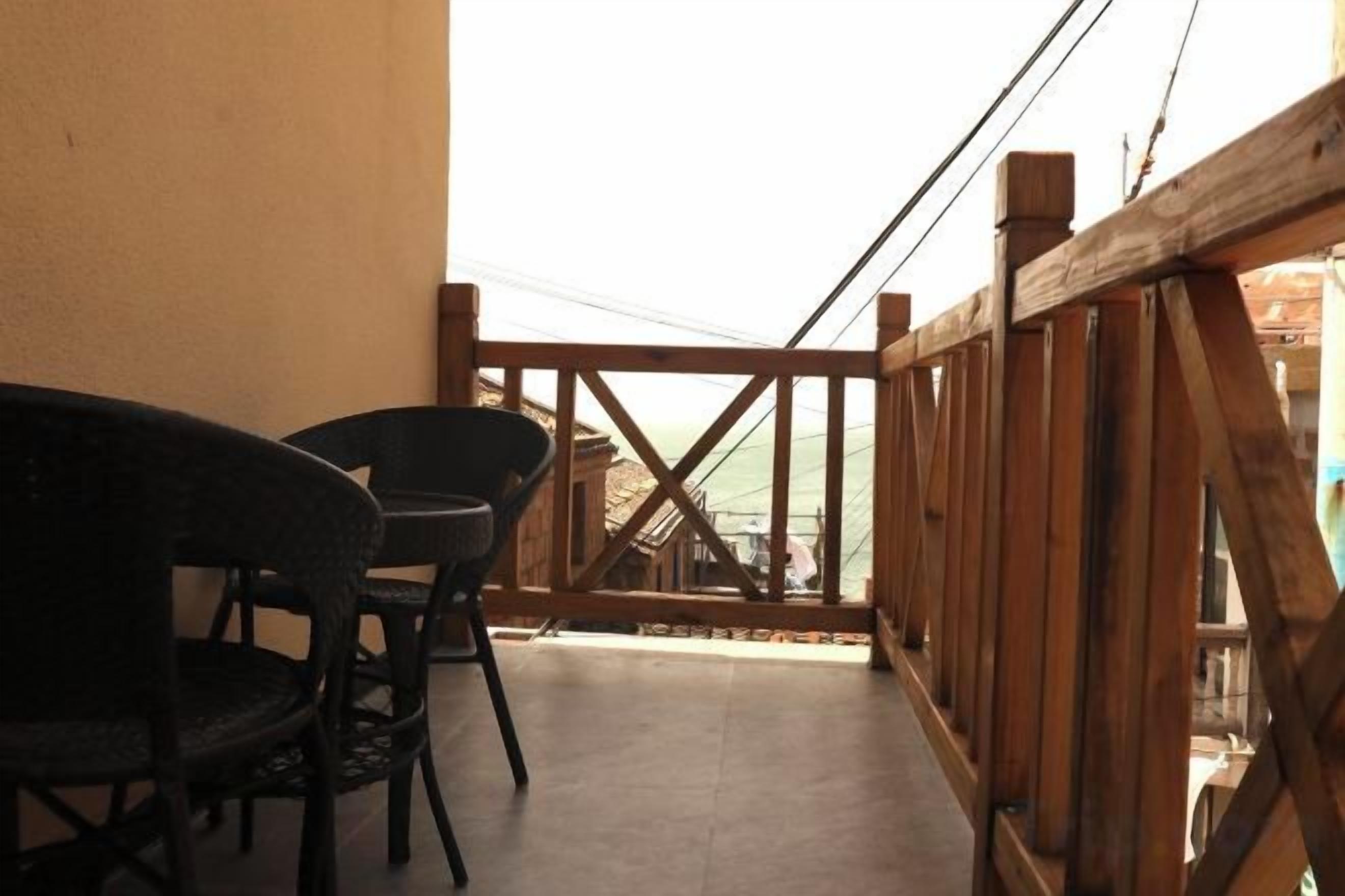 A balcony with two chairs and a wooden railing.