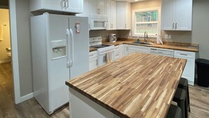 Une cuisine moderne avec des meubles blancs, un plan de travail en bois et un îlot central.