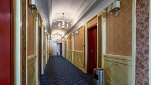 A hotel hallway with patterned carpet, wooden doors, and wall-mounted lighting. - Concept hotel (Ziyang)