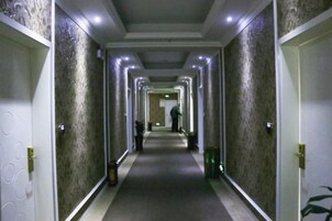 Un pasillo largo y estrecho con puertas a ambos lados, que conduce a una habitación al final.