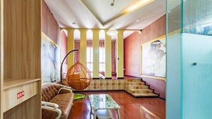 A modern interior with a wooden floor, a hanging chair, a sofa, a table, and a staircase. - Concept hotel (Ziyang)