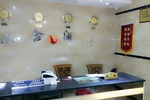 Zona de recepción con mostrador, sillas, relojes y un banner rojo con caracteres chinos.