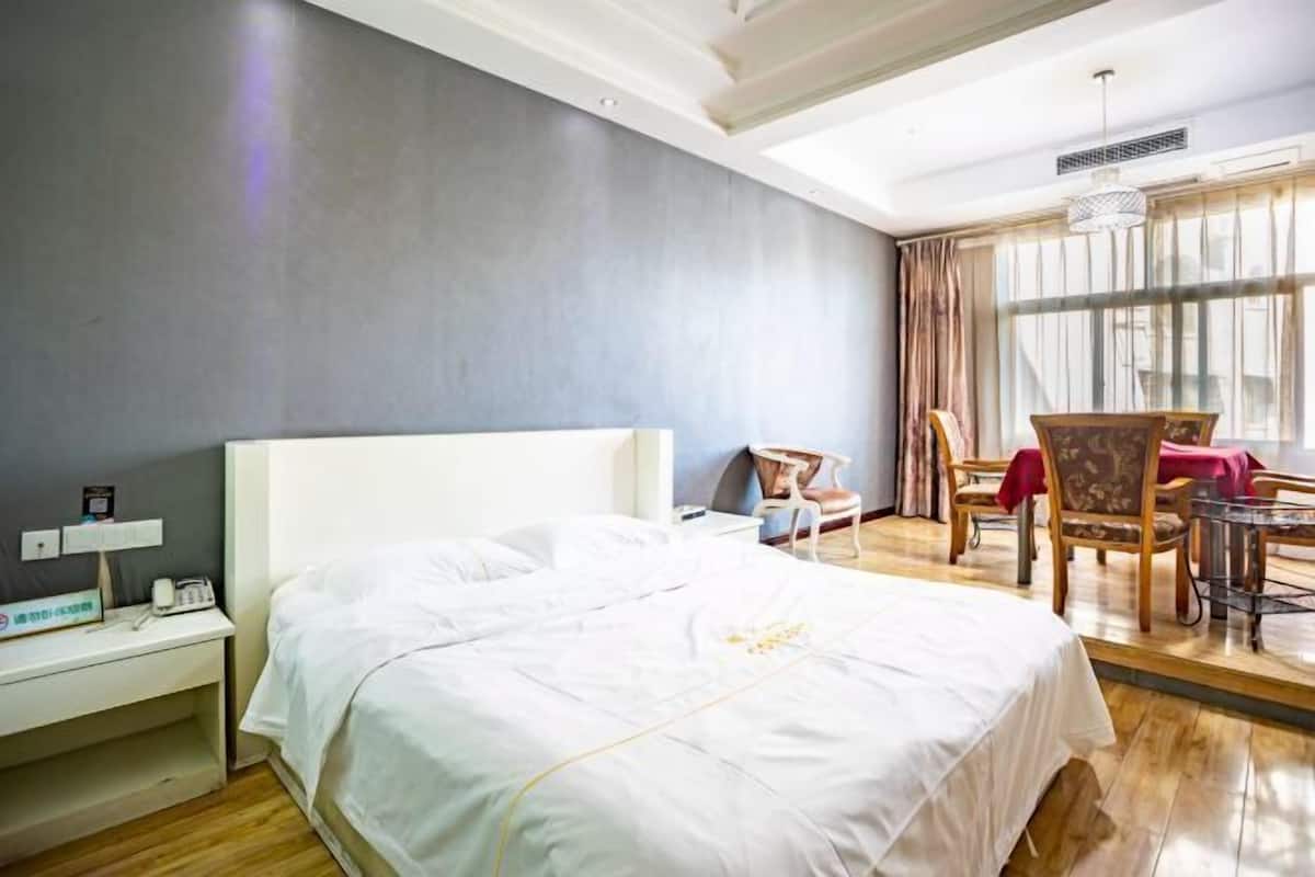Una habitación de hotel con una cama grande, un escritorio con teléfono y un comedor con sillas y una mesa.