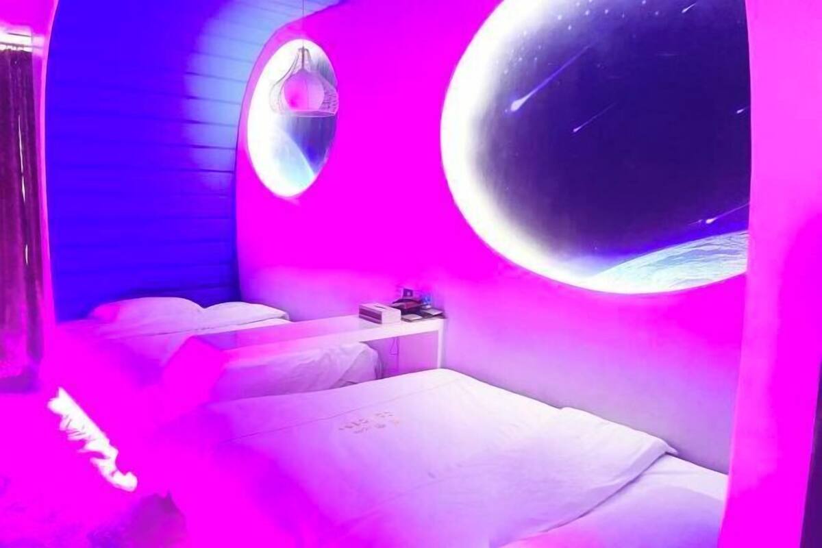 Una habitación con cama, mesita de noche, espejo en la pared y un ventanal grande.