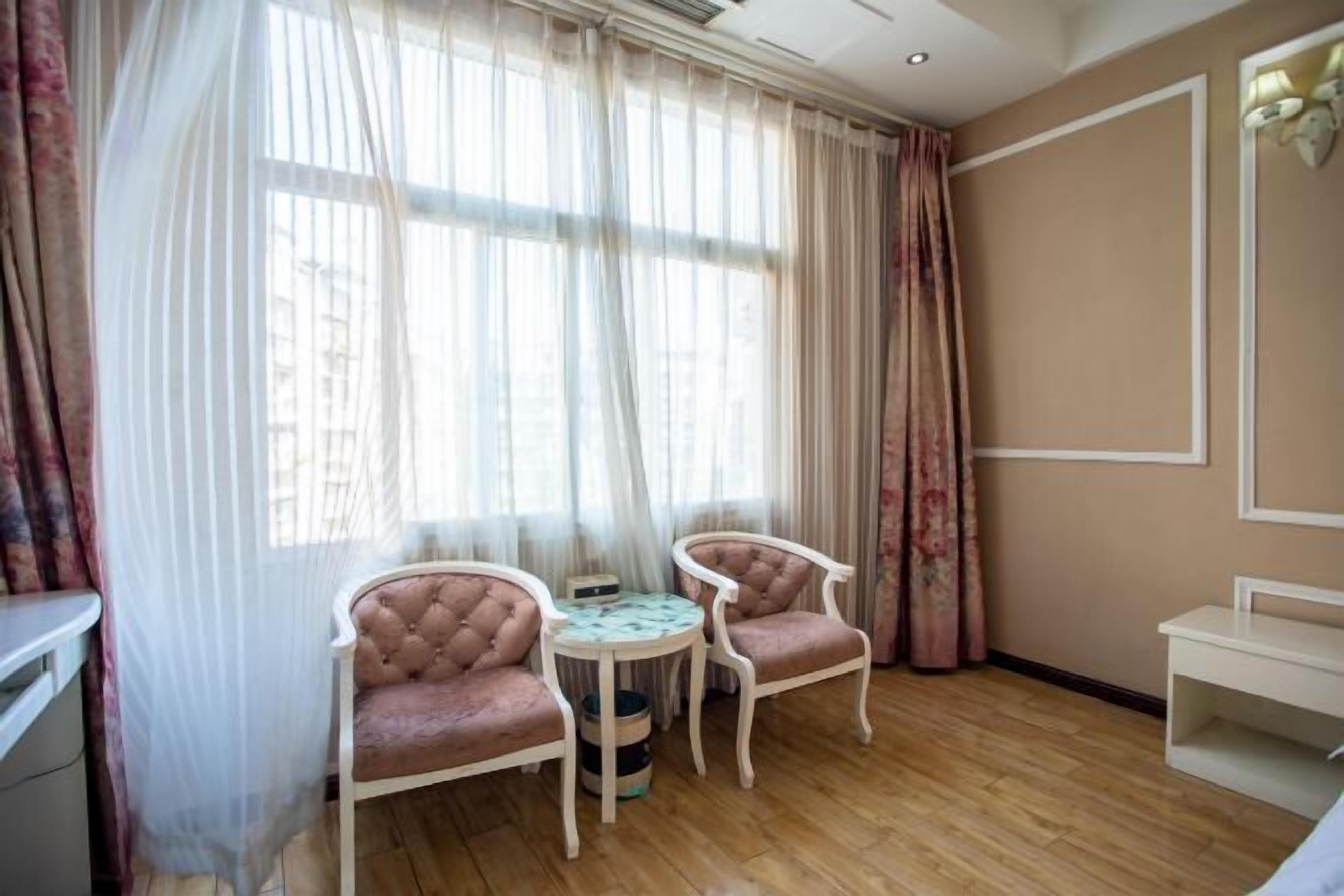A room with two upholstered chairs, a small round table, and a white bench.