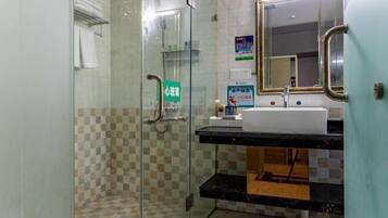 Une salle de bain avec une douche à parois de verre, un lavabo avec un miroir et un porte-serviettes.