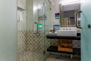 A bathroom with a glass shower enclosure, a sink with a mirror, and a towel rack.