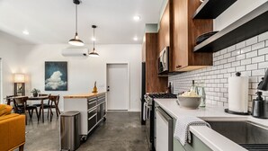 Une cuisine moderne avec des carreaux de céramique blancs disposés en motif métro, des armoires en bois et des appareils électroménagers en acier inoxydable.
