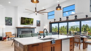 Una cocina moderna con una isla central, armarios de madera y un ventanal con vistas a un bosque.