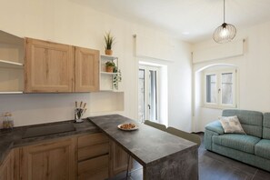 Eine moderne Küche mit Holzausstattung, einer zentralen Kochinsel und einem Essbereich mit einer Couch.
