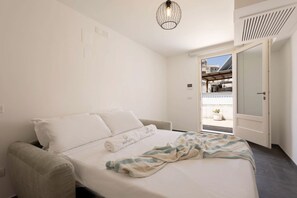 Ein Hotelzimmer mit Bett, Stuhl, einer Hängelampe und einer Tür zu einem Außenbereich.
