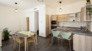 Une cuisine moderne avec des meubles en bois, un plan de travail en granit et deux suspensions lumineuses.