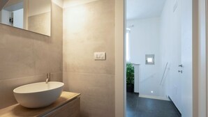 Une salle de bain moderne avec un grand lavabo rond, un miroir et un espace douche.