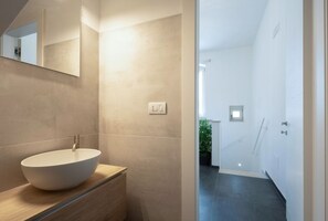 Ein modernes Badezimmer mit einem großen, runden Waschbecken, einem Spiegel und einer Duschkabine.