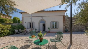 Un bâtiment doté d’un patio aménagé avec du mobilier d’extérieur, une table sur laquelle est posé un chapeau et une plante en pot.
