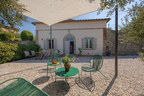 A building with a patio area featuring outdoor furniture, a table with a hat, and a potted plant. - Piccola Fonte - come by car and you'll have everything at your fingertips (Camucia)