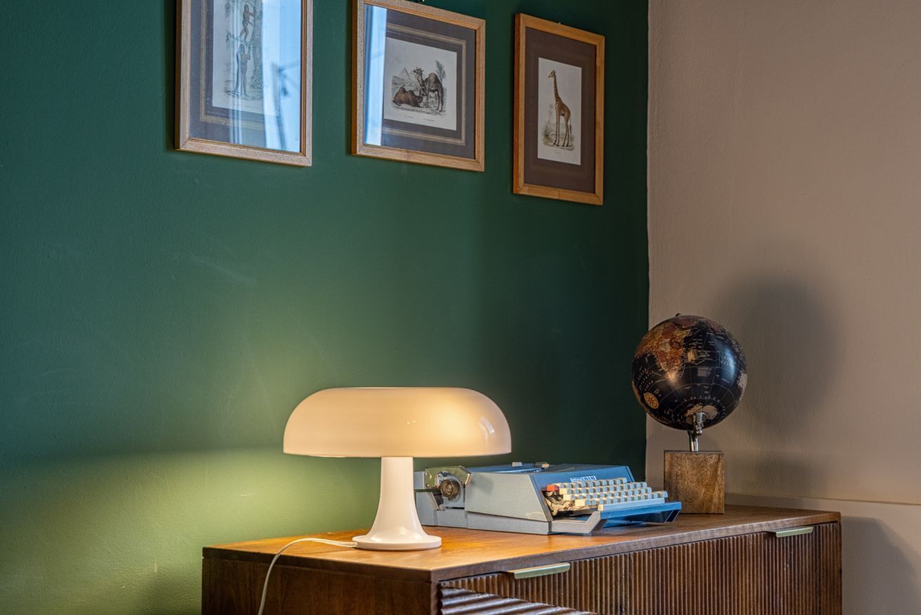 A desk with a lamp, a globe, and framed pictures on a wall.