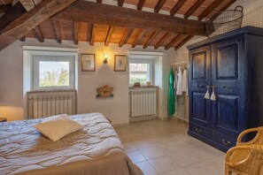 A bedroom with a bed, a radiator, a wardrobe, and a window.