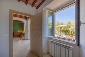 A room with a large window, a door, a radiator, and a view of an outdoor patio.