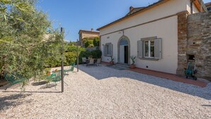 A villa with a gravel driveway, outdoor seating, and a stone wall.
