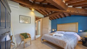Une chambre avec un plafond en bois, un lit, une chaise et un miroir.