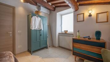 Une pièce avec un plafond en bois, une armoire de couleur turquoise, un radiateur, une fenêtre et une commode en bois.