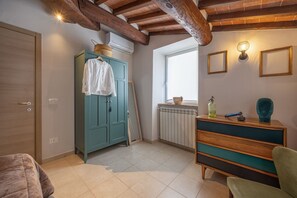 Une pièce avec un plafond en bois, une armoire de couleur turquoise, un radiateur, une fenêtre et une commode en bois.