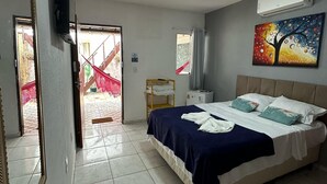 Une chambre à coucher comprenant un lit, une télévision, un climatiseur, une fenêtre et une porte donnant sur un espace extérieur.