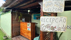 Un espace d’accueil avec un bureau en bois, une chaise et une pancarte indiquant « Bem Vindo Welcome » et « Recepção ».