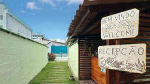 Un chemin menant à un bâtiment sur lequel on peut lire les inscriptions « Bienvenue » et « Réception », le tout étant entouré d’une pelouse verdoyante et d’un mur de briques.
