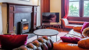 A cozy living room with a fireplace, leather sofa, and a television. - 5 bedroom accommodation in Blackwaterfoot (Blackwaterfoot)