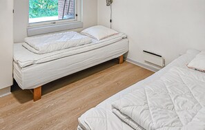 A single bed with a wooden frame in a room with a window, a radiator, and a power outlet on the wall. - Gorgeous home in Oksbøl with sauna (Oksbøl)
