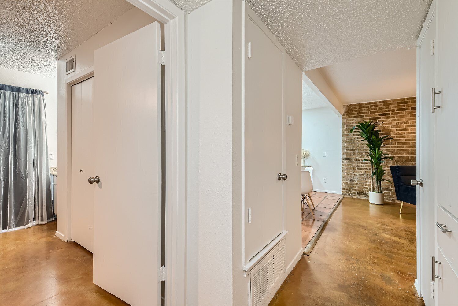 Ein Flur mit weißen Türen, einer Backsteinwand und einem Blumentopf.