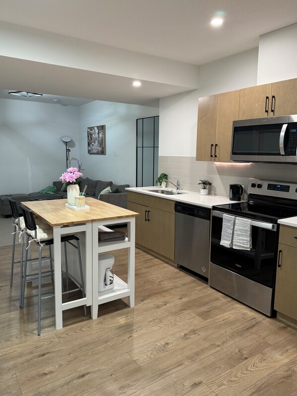 Una cocina moderna con comedor, armarios de madera, electrodomésticos de acero inoxidable y un diseño minimalista.
